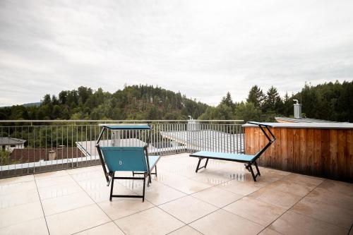 a patio with two chairs and a bench on a balcony at OpenSky Wörthersee Lodge in Pörtschach am Wörthersee