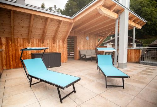 a patio with two blue chairs and a grill at OpenSky Wörthersee Lodge in Pörtschach am Wörthersee