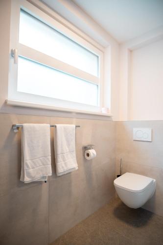 a bathroom with a toilet and a window and towels at OpenSky Wörthersee Lodge in Pörtschach am Wörthersee