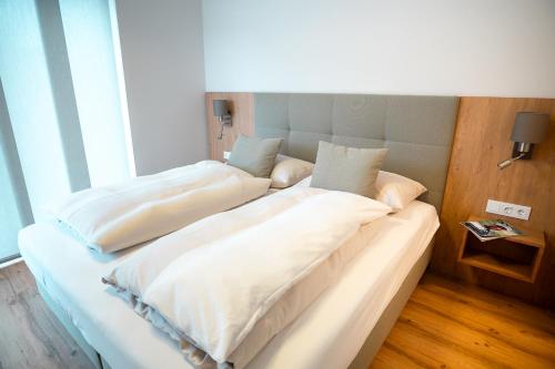 two beds in a hotel room with white sheets at OpenSky Wörthersee Lodge in Pörtschach am Wörthersee