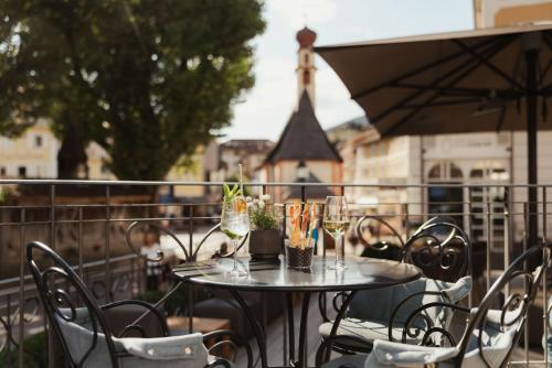 a table with chairs and wine glasses on a balcony at Hotel Genziana in Ortisei