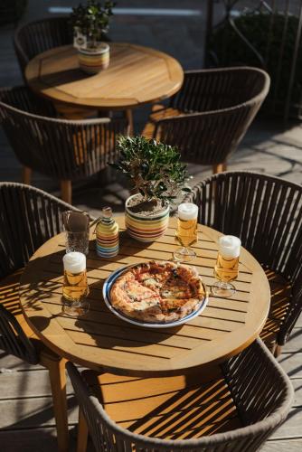 a wooden table with a pizza and glasses of beer at Hotel Genziana in Ortisei