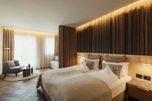 a hotel room with a large bed and a chair at Hotel Genziana in Ortisei