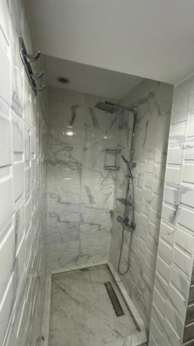 a bathroom with a shower with white tiles at Duplex imiouaddar in Agadir nʼ Aït Sa