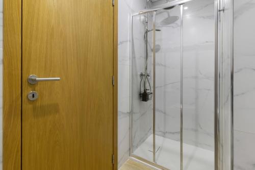 a bathroom with a shower with a wooden door at Al Do Paço - Between Braga e Geres in Amares