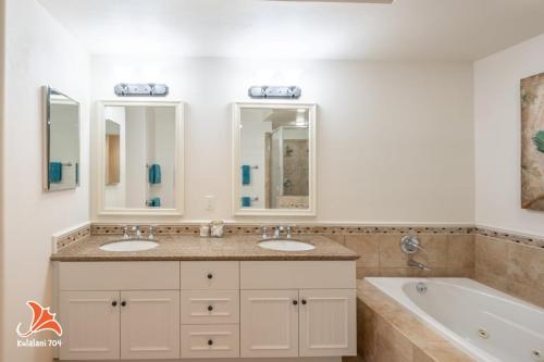 a bathroom with two sinks and a tub and two mirrors at 2BR bright quiet condo in Kulalani sleeps 6 in Waikoloa