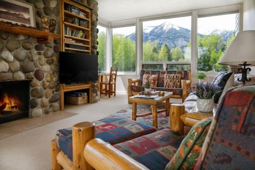 a living room with a fireplace and a stone wall at RMR: Lupine 1911 Condo in The AspensWilsonWY in Wilson