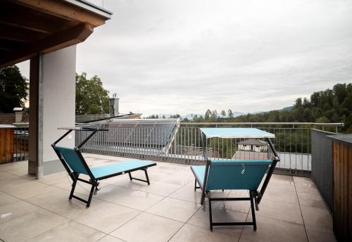 two chairs and a table on a balcony at OpenSky Wörthersee Lodge in Pörtschach am Wörthersee