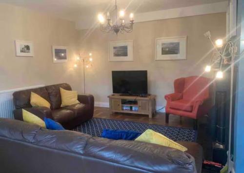 a living room with a leather couch and a red chair at Enniscrone House in Enniscrone