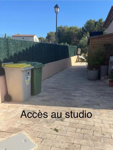 a garbage can on a patio next to a fence at Studio calme entre Aix et Marseille in Les-Pennes-Mirabeau