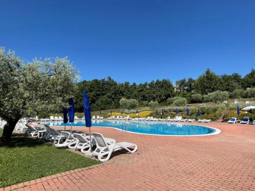 a group of chairs and umbrellas next to a swimming pool at Wendy House RESIDENCE CORTE COLLINA in Castion Veronese