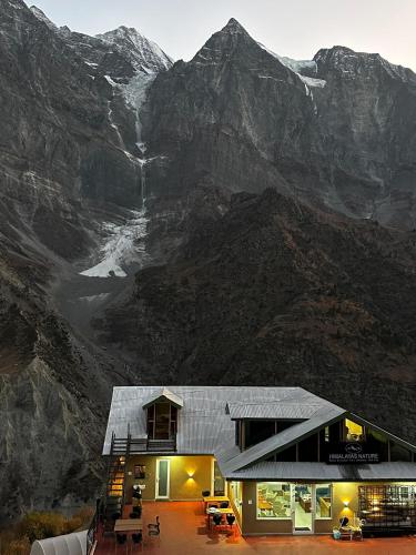 a large building with a mountain in the background at Himalayas Nature Lahaul in Gondla