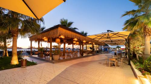 a restaurant with tables and chairs and palm trees at Gloria Palace Hotel & SPA in Golem
