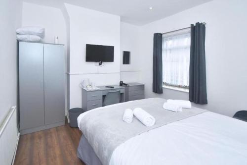 a white bedroom with a bed with two towels on it at Stylish 3bedroom near Stoke-on-Trent hospital in Stoke on Trent