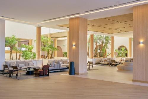 a lobby with chairs and tables and palm trees at PortoBay Blue Ocean in Albufeira