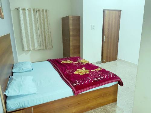 Una cama con una manta roja encima. en Shree Radharani Dham, en Vrindāvan