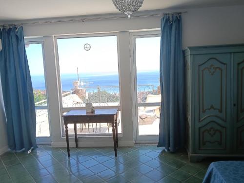 a room with a table in front of large windows at Villa vista mare in Varazze