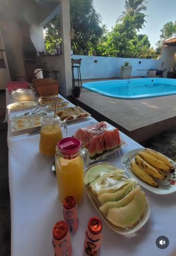 a table with food and drinks on it with a pool at Nosso Quintal in Santo Amaro