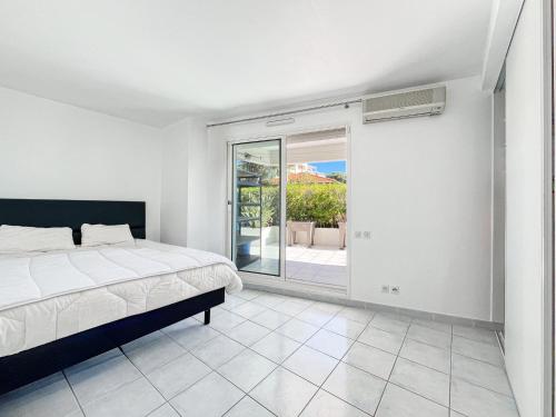 una camera da letto con un letto e una porta scorrevole in vetro di Grand bleu Front de Mer Magnifique 3 Pièces garage a Antibes