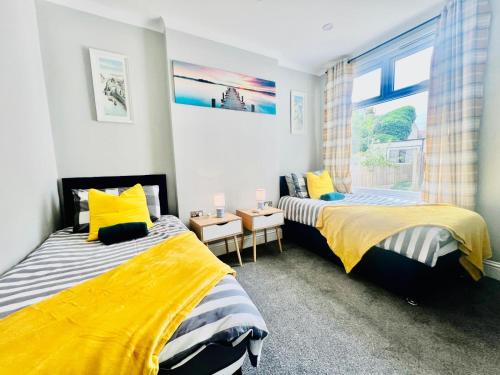 two beds in a room with a window at Deluxe Apartment in Southend-On-Sea by Artisan Stays I Free Parking I Sleeps 5 in Southend-on-Sea
