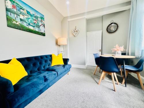 a living room with a blue couch and a table at Deluxe Apartment in Southend-On-Sea by Artisan Stays I Free Parking I Sleeps 5 in Southend-on-Sea