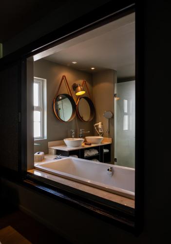 a bathroom with a large tub and two mirrors at Majeka House Boutique Hotel by The Living Journey Collection in Stellenbosch