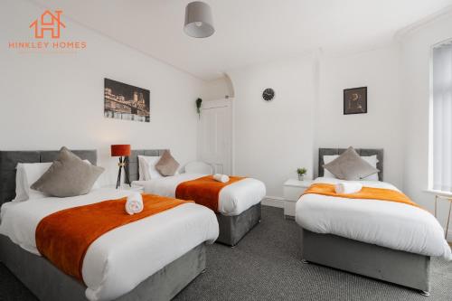 a bedroom with two beds with orange and white sheets at 9 Guests, 4 Bedrooms, Modern Comfort in Bootle in Litherland