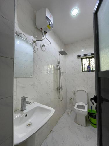 a white bathroom with a sink and a toilet at Dearest service apartment in Lagos