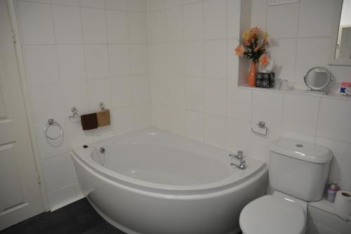 a white bathroom with a toilet and a bath tub at Sherwood Lodge in Skegness