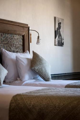 a bed with white pillows and a picture of a man at Riad Hanael Garden & Spa in Fès