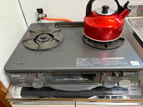 a red tea kettle sitting on top of a stove at Nikko-Imaichi "The LINKs" Dormitory House in Nikko