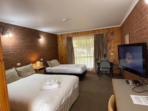a hotel room with two beds and a flat screen tv at Country Roads Motor Inn in Narrandera