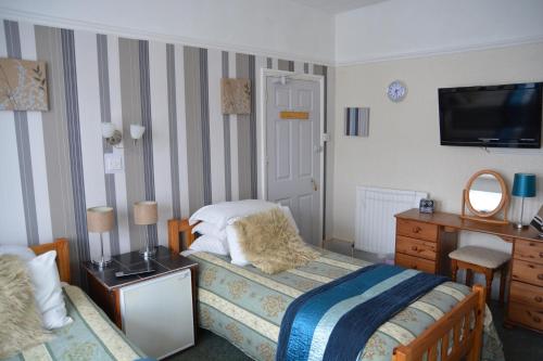 a bedroom with a bed and a dresser and a television at Sherwood Lodge in Skegness