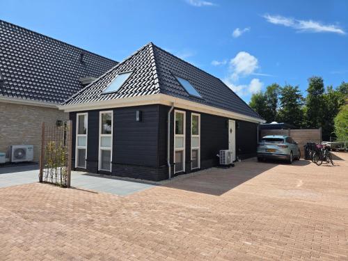 a black house with a roof on a brick driveway at Heidezee in Dishoek in Dishoek