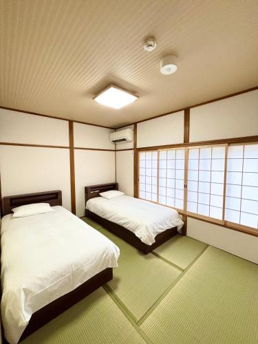 two beds in a room with windows at Kyoto Station Lanshin in Kyoto