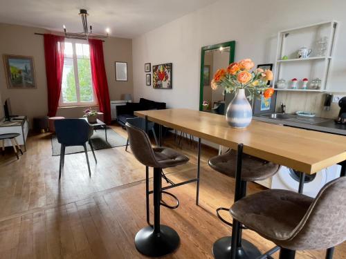 a living room with a table with a vase of flowers on it at Appartements de Diane - JOIGNY in Joigny