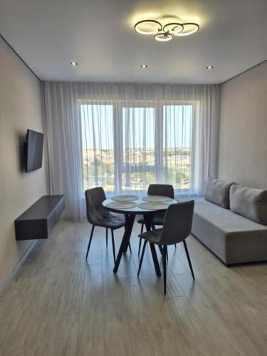 a living room with a couch and a table and chairs at Апартаменти на Марсельській 62 в ЖК Острова, 1 спальня та кухня-студія in Odesa