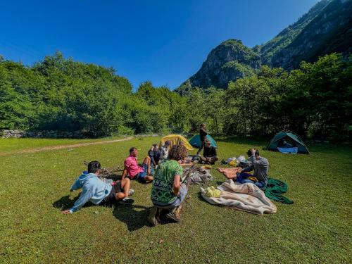a group of people sitting on the grass in a field at Hostel 90pods & C O working in Shkodër