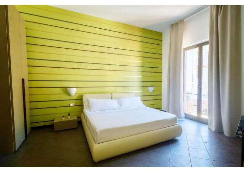 Un dormitorio con una cama blanca y una pared amarilla. en Il Sogno, en Milazzo