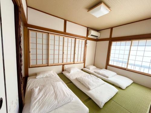 three beds in a room with two windows at Kyoto Station Lanshin in Kyoto