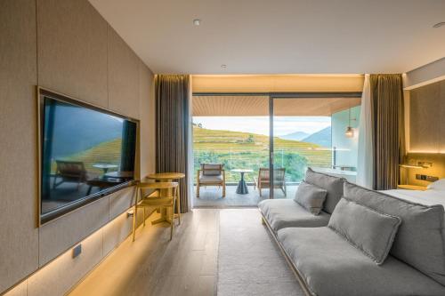 a living room with a couch and a large tv at Longji Vista Retreat--Panoramic View of Terrace, Sunrise ,Heated Pool & Affordable Luxury in Longsheng