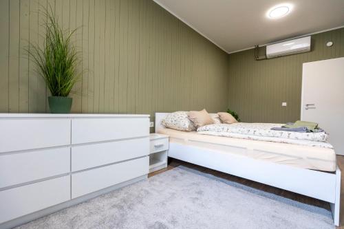 a bedroom with a bed and a white dresser at Park Apartman in Sarród