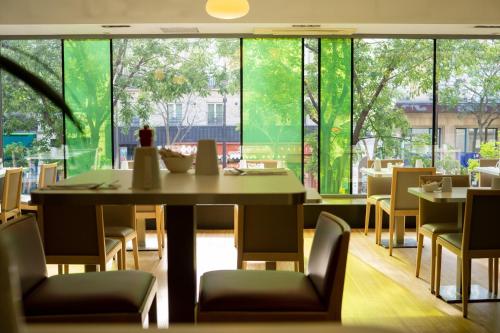 a dining room with a table and chairs and large windows at Holiday Inn Paris Opéra - Grands Boulevards by IHG in Paris