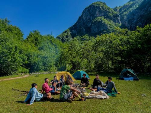 a group of people sitting in the grass near tents at Hostel 90pods & C O working in Shkodër
