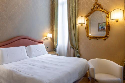 a bedroom with a white bed and a mirror at Hotel Colombina in Venice