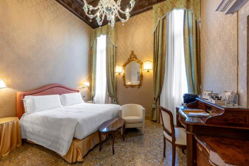 a bedroom with a bed and a desk and a mirror at Hotel Colombina in Venice