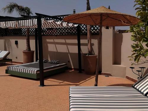 - une terrasse avec 2 lits et un parasol dans l'établissement Riad Yakimour, à Marrakech