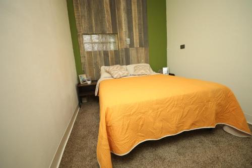 a bedroom with a bed with an orange bedspread and a window at Xio's House in Manuel F. Martínez