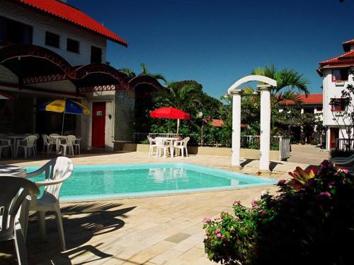 a swimming pool with chairs and a table and umbrella at Residencial Sol e Mar de Floripa in Florianópolis