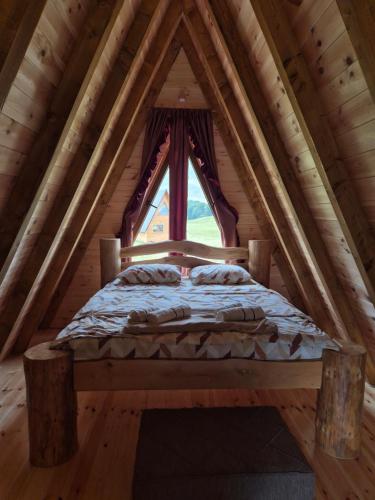 Ce lit se trouve dans une cabane en rondins dotée d'une fenêtre. dans l'établissement Cottage forest hill 2, à Žabljak